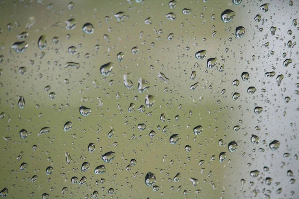 Close up of glass with raindrops on natural background, drops of water on car glass, selective focus