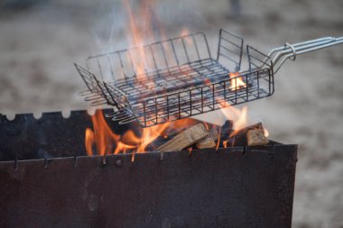 Kumlu kumsalda yanan odun ızgaraları, yaz pikniği konsepti