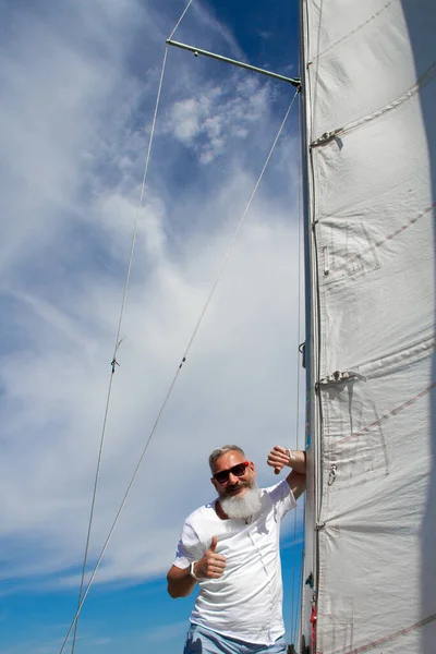 Glad senior man på segelbåt eller yacht flyter i havet. Ålderdom turism och resor koncept. — Stockfoto