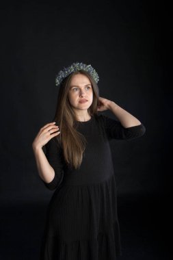 Siyah arka planda kurumuş çiçek çelengi içindeki güzel esmer kızın stüdyo portresi, duygusal konsept.