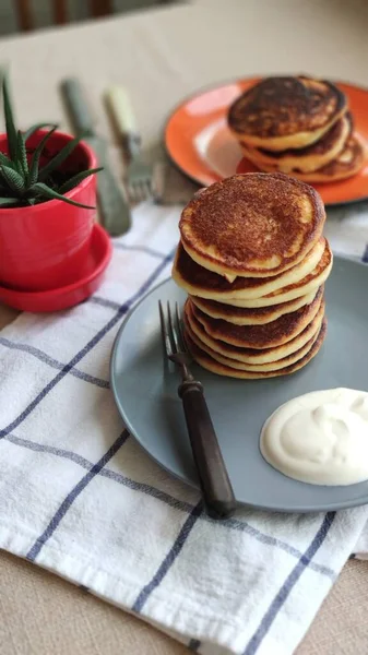 Teller mit hausgemachten Pfannkuchen und saurer Sahne auf Holztisch, selektiver Fokus — Stockfoto