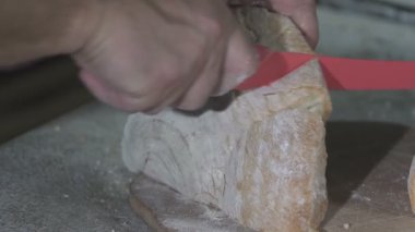 Baker ekmek bıçağıyla sıcak ekmek taze keser. ağır çekim