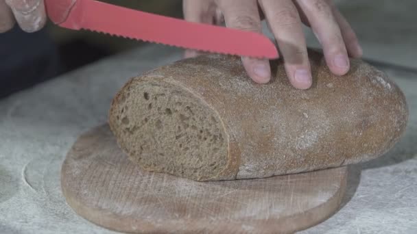 Baker cuts hot fresh bread. slow motion — Stock Video