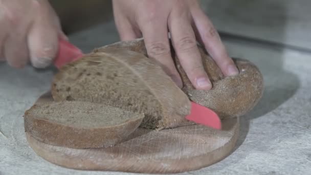 Baker cuts hot fresh bread. slow motion — Stock Video