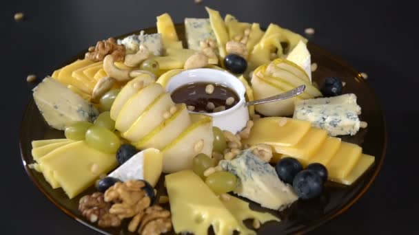 Platou de brânză presărat cu nuci de pin. mișcare lentă — Videoclip de stoc