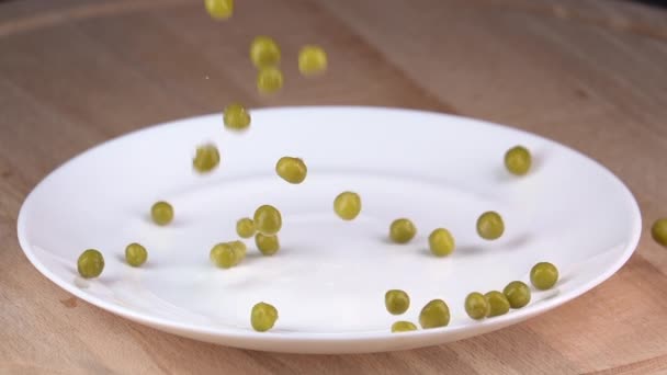 Зеленый горошек падает на тарелку. Медленное движение 250 кадров в секунду — стоковое видео
