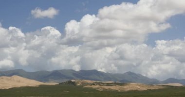 4k beyaz kabarık bulut kitle dağın üzerinde haddeleme ve kum tepeleri çöl.