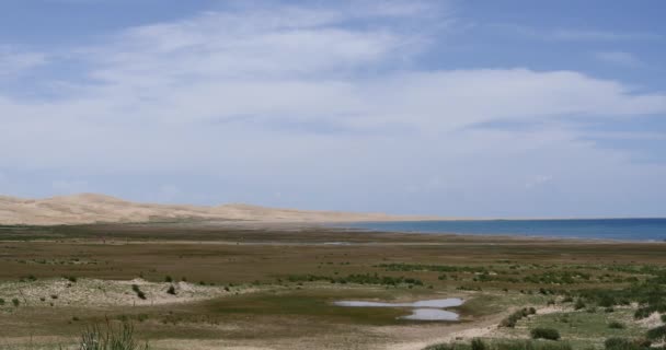 4k far away desert sand dunes,white puffy cloud mass rolling over blue lake. — Stock Video