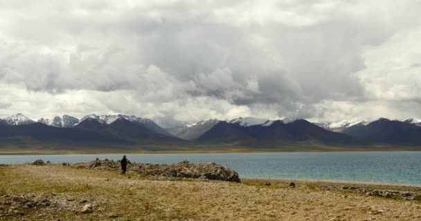 4k тибетцев ходьба паломник на озере namtso в Тибете, снежная гора . — стоковое видео