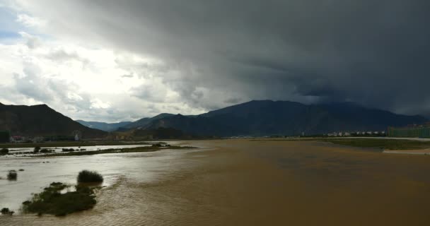 4k rio Lhasa, longe nuvens escuras massa rolando sobre o Tibete montanha . — Vídeo de Stock