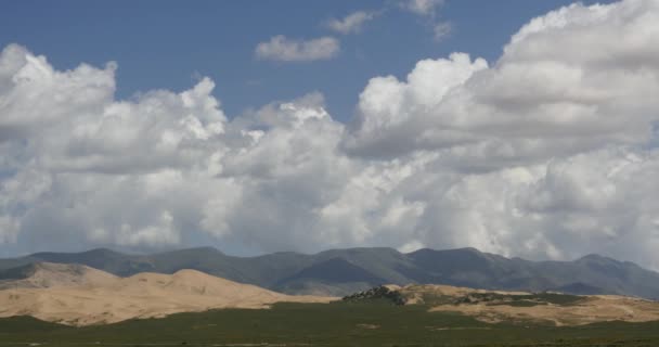 4k masa de nubes hinchadas blancas rodando sobre la cima de la montaña y las dunas de arena del desierto . — Vídeos de Stock