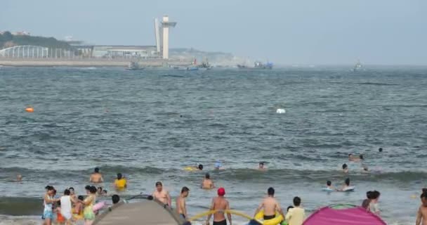 4k muchas personas en la playa de arena llena de gente, la gente nadando en el mar . — Vídeos de Stock