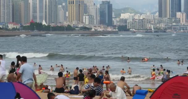 4k molte persone in spiaggia sabbiosa affollata.Persone che nuotano in mare, QingDao, Cina . — Video Stock