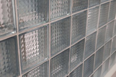 Yakından bakıldığında, odanın atmosferini geliştiren ve ışığı yakalayıp kıran geometrik desenlere sahip net cam bloklardan oluşan bir küme görülür..