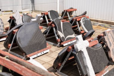 Granit mezar taşları bir taş bahçesinde sergileniyor. Ayar parlak ve güneşli, taşların çeşitli tasarım ve dokularını vurguluyor..