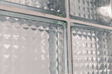 Işığın geçmesine izin veren çeşitli dokulara sahip cam blokların yakın görüntüsü. Tasarım, doğal ışıkla dolu çağdaş bir alanda ilginç bir görsel efekt yaratıyor..