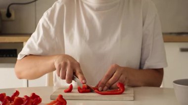 Parlak bir mutfakta, bir kadın sebze hazırlamaya odaklanır. Tahta kesme tahtasındaki taze havuçları ustalıkla dilimliyor. Mutfak becerilerini ve detaylara olan ilgisini gösteriyor..