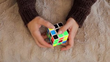 Chemnitz, Almanya - 06-09-2025: Yakından bakınca renkli Rubiks Küpü 'nü çözmeye odaklanmış bir kadın görülüyor. Elleri bulmacayı ustalıkla manipüle ediyor. Konsantrasyonunu ve kararlılığını gösteriyor.