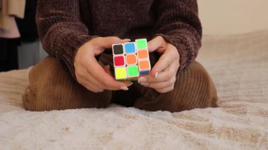 Chemnitz, Almanya - 06-09-2025: Rubiks küpüyle yakınlaşan bir kadının renkli bulmacayı çözmek için çalışırken yoğun konsantrasyonunu sergilemesi