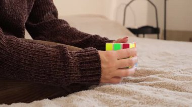 Chemnitz, Almanya - 06-09-2025: Bir kadın kapalı bir ortamda renkli bir bulmacayı çözmeye odaklanıyor. Parçaları dikkatle inceliyor ve manipüle ediyor. Kararlılığını gösteriyor..