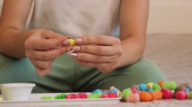 Bir kadın, çocuklar için uygun renkli mısır malzemelerini kullanarak el sanatları faaliyetlerine girişir. Kapalı alandaki çevre dostu kreasyonlar üzerinde yoğunlaşıyoruz..