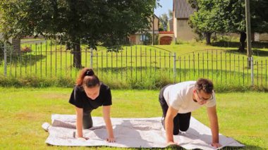 Bir çift arka bahçelerinde bir fitness seansına katılıyor, birlikte çeşitli egzersizler yapıyorlar. Sağlıklı bir yaşam sürerken güneşli havanın tadını çıkarıyorlar..