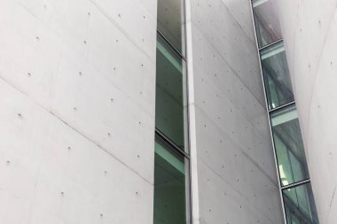 Çarpıcı cephede, kentsel mimaride temiz ve modern bir estetiği yansıtan geniş cam panellerle zıt düz beton duvarlar yer alıyor..