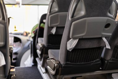 Gündüz vakti bir şehir otobüsünün içinde, sahne düzgünce düzenlenmiş boş koltukları gösteriyor. Pencerelerden süzülen güneş ışığıyla atmosfer sakin, iç detayları vurguluyor..