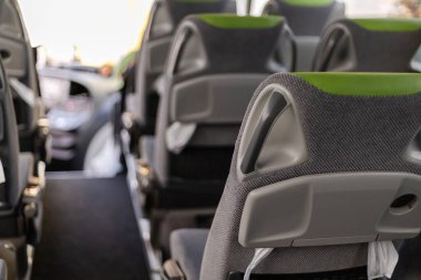 Bir otobüsün içi konfor için tasarlanmış modern koltukları gösteriyor. Parlak ışıklandırma karşılama atmosferini güçlendirir. Şehirde rahat bir yolculuk için ideal..