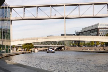 Berlin, Almanya - 1 Eylül 2025: Şehir hayatı, güneşli bir günde modern mimari ve zarif köprülerle çevrili Berlin 'in sakin sularında yüzen bir tekne olarak gözler önüne seriliyor.