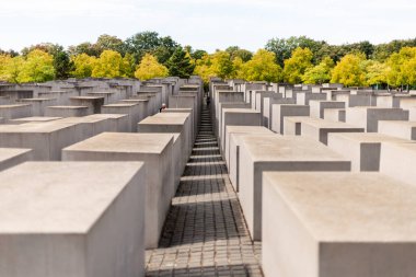 Berlin, Almanya - 1 Eylül 2025: Ziyaretçiler Berlin 'de öldürülen Avrupa Yahudileri Anıtı' nı keşfediyorlar. Görüntü, gri beton blokların arasında huzurlu bir anı yakalıyor.