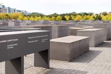 Berlin, Almanya - 1 Eylül 2025: Ziyaretçiler Berlin 'de öldürülen Avrupa Yahudileri Anıtı' nı büyük beton levhalarla çevrili olarak keşfediyorlar. Ayar derin düşüncelere dalan bir atmosferi yakalıyor.