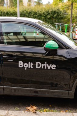 Berlin, Almanya - 1 Eylül 2025: Bir Bolt Drive aracı yoğun bir Berlin caddesinde park halinde duruyor. Yeşil aksanlar, canlı bir şehir atmosferinin yanında, kentsel hareketlilik gösteren arabayı ön plana çıkarıyor.