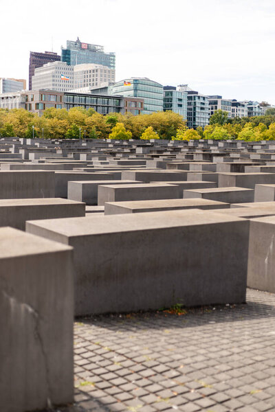 Берлин, Германия - 1 сентября 2025 года: Огромный массив бетонных блоков создает мощный мемориал в Берлине. Ясное небо усиливает картину, так как деревья обеспечивают прикосновение природы среди городского ландшафта