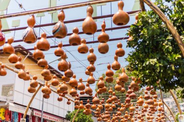 Alanya, Türkiye - 10 Temmuz 2025: Alanya 'daki canlı bir pazarda, bir çerçeveye birden fazla el yapımı su kabağı sarkıyor ve sıcak güne şenlikli bir süsleme ekliyor