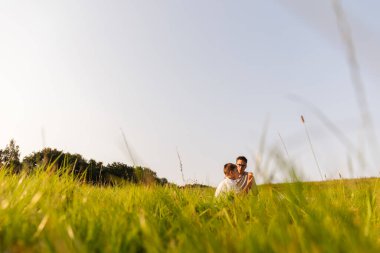 Bir baba ve oğlu yemyeşil bir alanda birlikte rahatlar, kahkahalar ve hikayeler paylaşırlar. Sıcak güneş batıyor, kaynaşma ve macera için neşeli bir atmosfer yaratıyor..