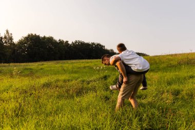 Onlar canlı yeşil bir çayırı keşfederken bir baba oğlunu sırtında taşır. Sıcak akşam ışığında kahkaha ve neşeyi paylaşıyorlar, bağlarını derinleştiriyorlar..