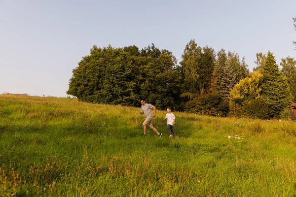 Bir çocuk ve babası yemyeşil bir arazide neşeyle koşuyorlar. Güneş parlıyor ve ağaçlar güzel bir zemin sağlıyor. Açık havada şakacı bir bağ kuruyorlar..