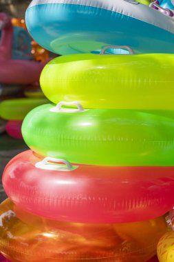 Parlak renkli şişme havuz şamandıraları bir araya yığılır ve yüzme alanının yakınında canlı bir görüntü oluşturur. Yaz eğlencesi ve havuz keyfi için mükemmel..