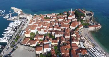 Uçuş eski şehir Budva, Karadağ yukarıda. Havadan görünümü eski geleneksel Balkan tarzı, eski kilise ve bir sahil deniz araçları ile şehir Budva, leyleklerin onun taş evler 
