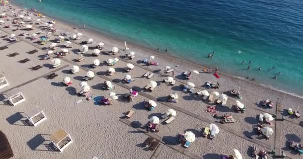 ブドヴァ モンテネグロ ブドヴァ ビーチ パラソルと日光浴 海で泳ぐ人の上を飛んでください — ストック動画