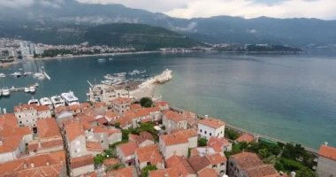 Uçuş eski şehir Budva, Karadağ yukarıda. Havadan görünümü eski geleneksel Balkan tarzı, eski kilise ve bir sahil deniz araçları ile şehir Budva, leyleklerin onun taş evler 