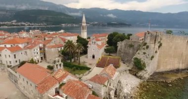 Uçuş eski şehir Budva, Karadağ yukarıda. Havadan görünümü eski geleneksel Balkan tarzı, eski kilise ve bir sahil deniz araçları ile şehir Budva, leyleklerin onun taş evler 