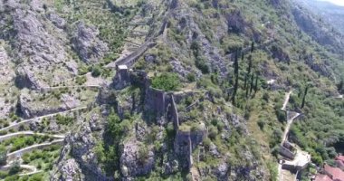 Uçuş eski Kotor antik kale kalıntıları yukarıda. Eski Kotor, dağlar ve Karadağ ulusal bayrak dağın tepesinde kale kalıntıları havadan görünümü