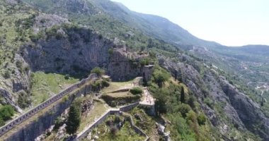 Uçuş eski Kotor antik kale kalıntıları yukarıda. Eski Kotor, dağlar ve Karadağ ulusal bayrak dağın tepesinde kale kalıntıları havadan görünümü