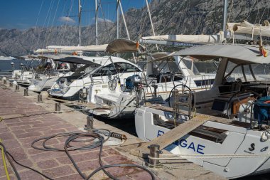 Büyük ve küçük beyaz Yatlar, motorlu tekne ve kürekli tekneler Adriyatik küçük kasabada Muo Kotor yakınındaki sahildeki iskelede palamarla. Görünümü bir Adriyatik kasabasının Marina