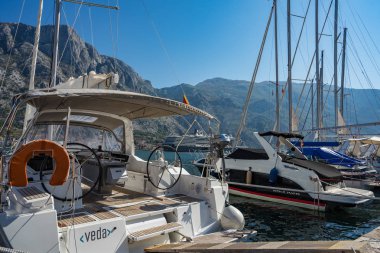 Büyük ve küçük beyaz Yatlar, motorlu tekne ve kürekli tekneler Adriyatik küçük kasabada Muo Kotor yakınındaki sahildeki iskelede palamarla. Görünümü bir Adriyatik kasabasının Marina