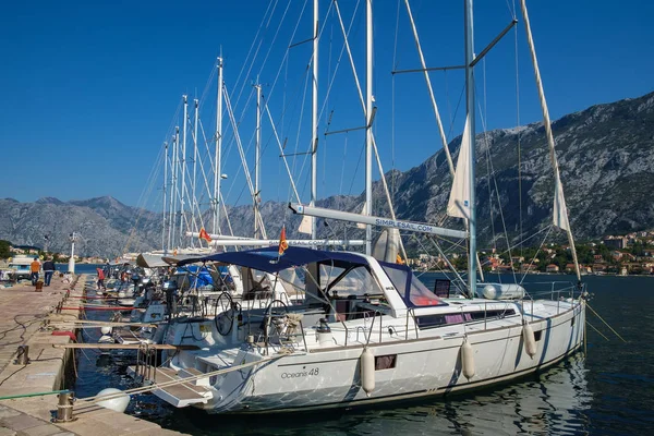 Büyük ve küçük beyaz Yatlar, motorlu tekne ve kürekli tekneler Adriyatik küçük kasabada Muo Kotor yakınındaki sahildeki iskelede palamarla. Görünümü bir Adriyatik kasabasının Marina