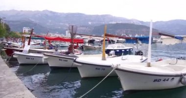 Budva, Karadağ 06 Ekim 2018: Adriyatik Denizi tabii. Balıkçı tekneleri Budva eski şehir yakınında sahildeki palamarla. Arka planda pitoresk dağlar görebilirsiniz