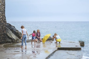 Budva, Karadağ, 06 Ekim 2018: Eğlenceli ve onların akıllı fotoğraf çekimi birbirlerinin şirket arkadaş - üç genç güzel kız - ve beş yıllık eski plajda yürüyor küçük bir kız kızlar var 